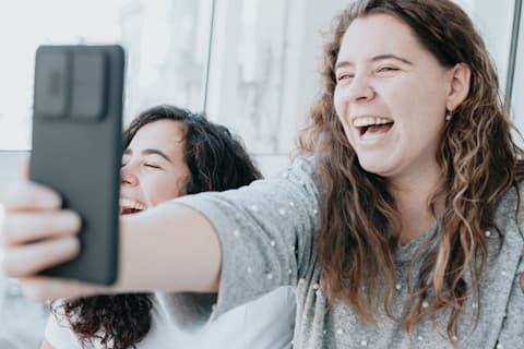 Two friends laughing while taking a selfie