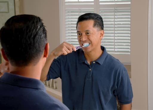 Man brushing his teeth in front of a mirror